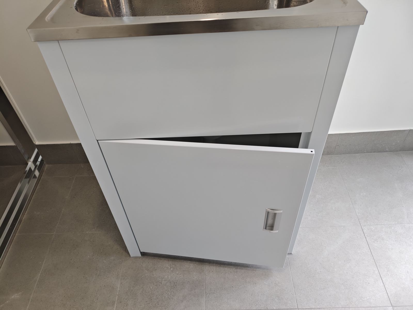 Laundry cabinet door hanging incorrectly, a workmanship defect found during inspection