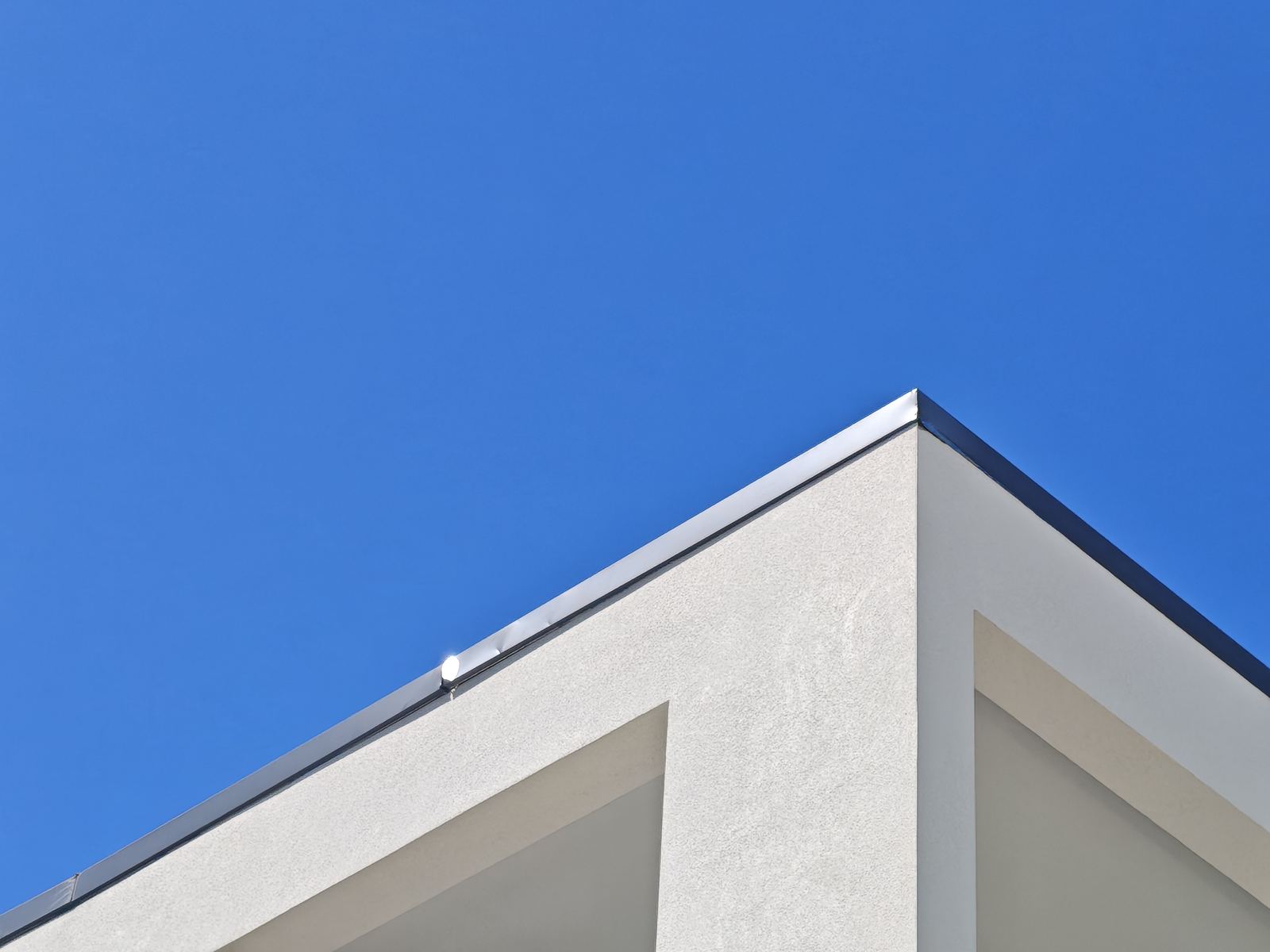 Clean modern roofline and wall corner against a clear blue sky