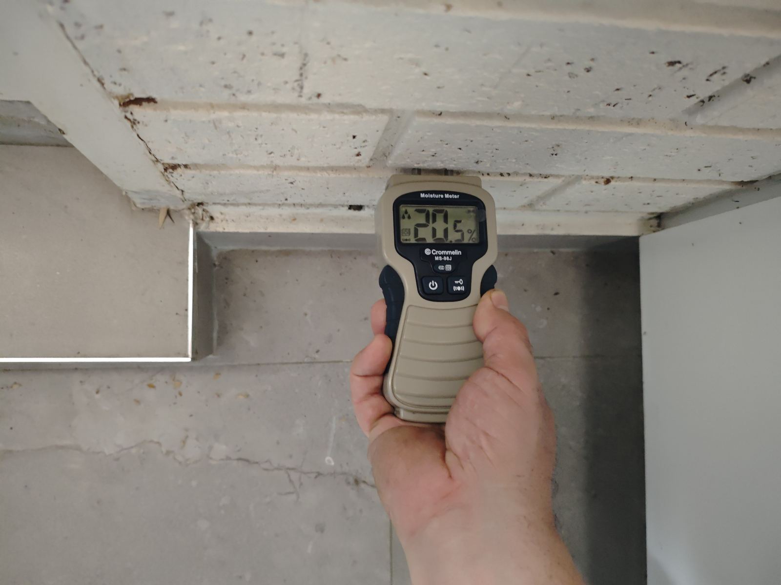 Akaki inspector using a moisture meter to test a ceiling for water ingress